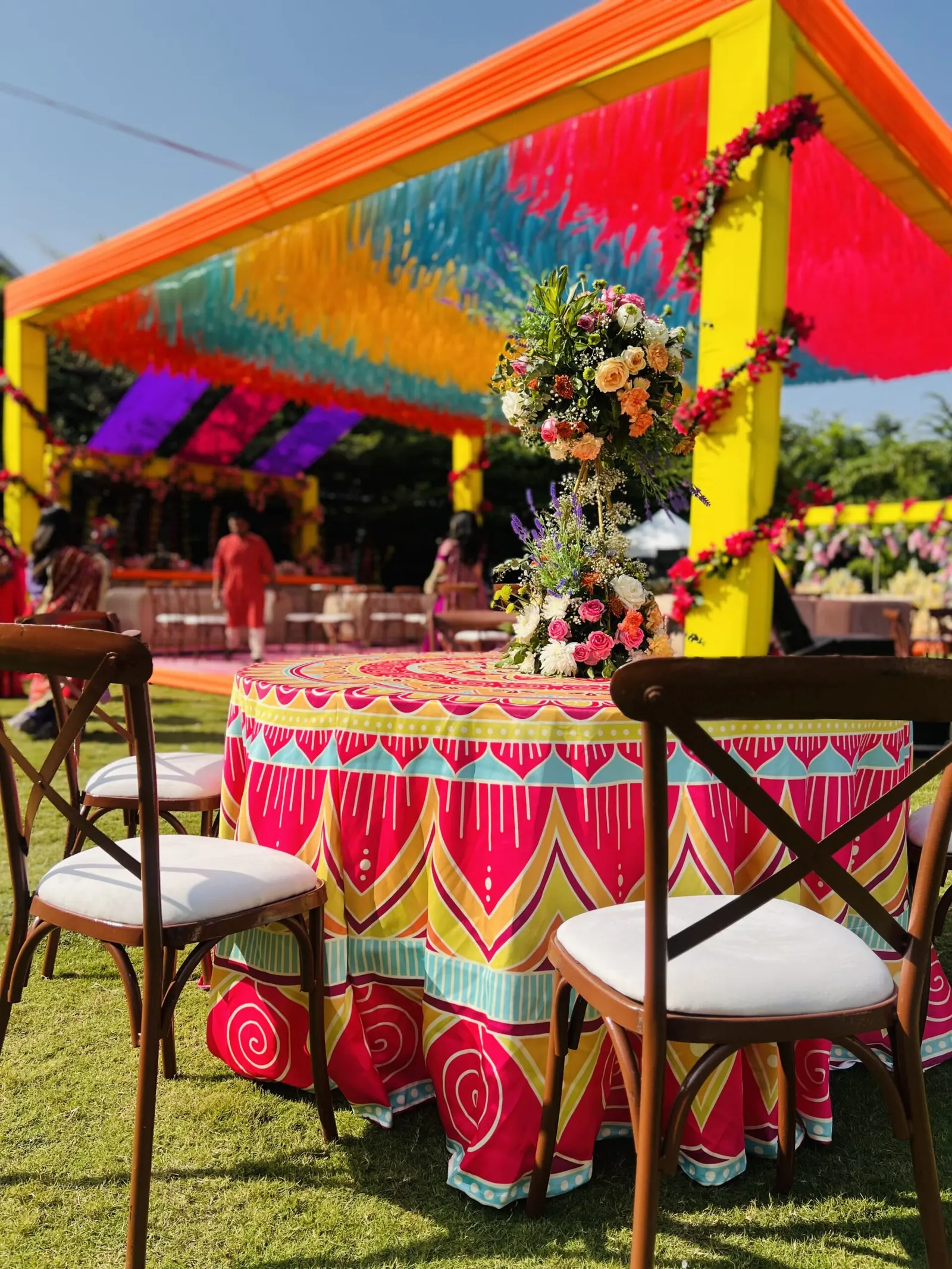 Colourful outdoor event setup with floral decor and draped canopy by Show Squad Events